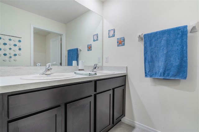 full bath featuring double vanity, baseboards, and a sink