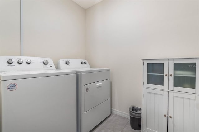 washroom featuring light tile patterned floors, cabinet space, baseboards, and washer and clothes dryer