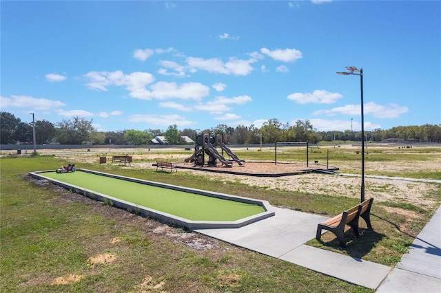 view of property's community featuring playground community and a yard