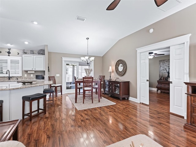 dining space featuring visible vents, baseboards, vaulted ceiling, ceiling fan with notable chandelier, and dark wood-style flooring