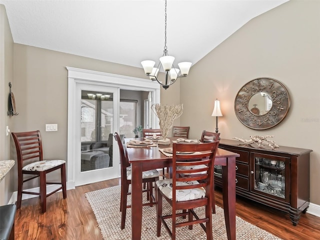 dining area with baseboards, wood finished floors, a chandelier, and vaulted ceiling