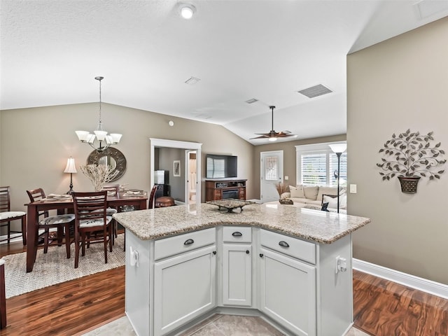 kitchen with visible vents, ceiling fan with notable chandelier, dark wood-style flooring, and vaulted ceiling