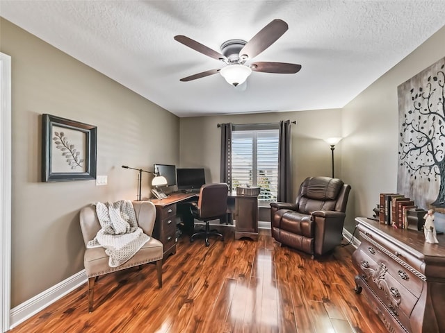 office area with a textured ceiling, baseboards, a ceiling fan, and dark wood-style flooring