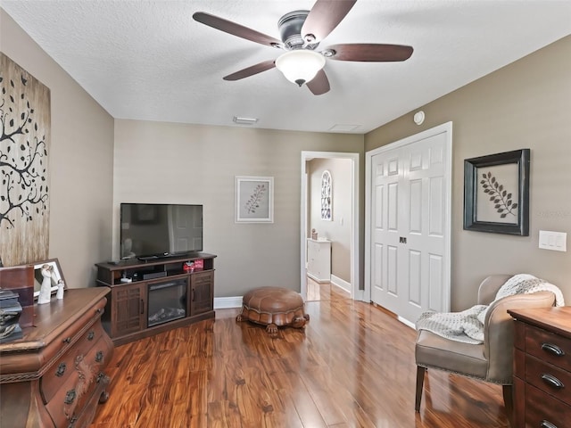 interior space featuring visible vents, a textured ceiling, wood finished floors, baseboards, and ceiling fan