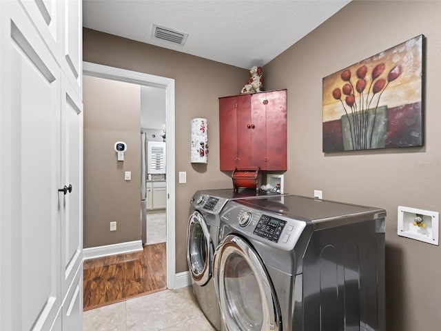 laundry area with light tile patterned floors, visible vents, baseboards, laundry area, and separate washer and dryer