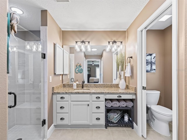 full bathroom featuring vanity, a stall shower, a textured ceiling, tile patterned floors, and toilet