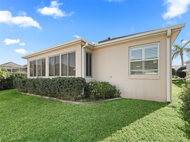 back of property featuring a lawn and stucco siding