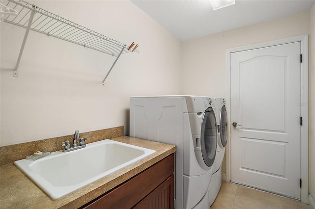 washroom featuring a sink, laundry area, light tile patterned flooring, and washer and clothes dryer