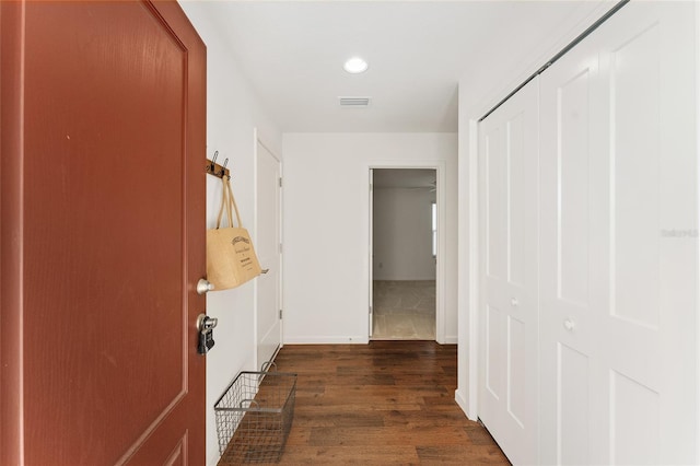 hallway with dark wood-type flooring, baseboards, and visible vents