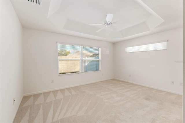 unfurnished room featuring light colored carpet, baseboards, a tray ceiling, and ceiling fan