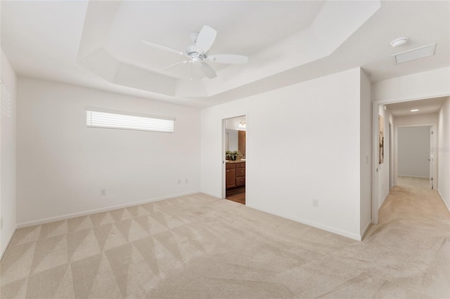 unfurnished room with baseboards, ceiling fan, light colored carpet, and a tray ceiling