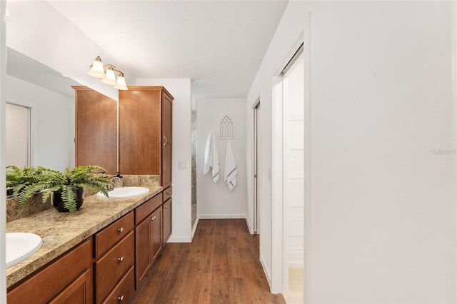 full bathroom with double vanity, wood finished floors, baseboards, and a sink