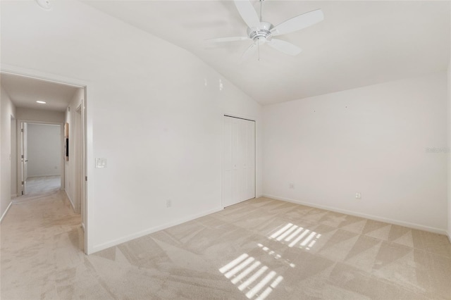 empty room featuring a ceiling fan, light colored carpet, baseboards, and high vaulted ceiling