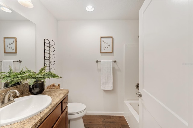 full bathroom featuring toilet, wood finished floors, washtub / shower combination, baseboards, and vanity