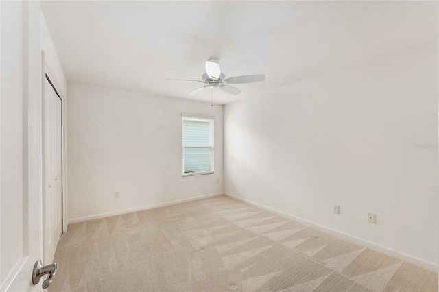 unfurnished bedroom with a closet, baseboards, light colored carpet, and a ceiling fan