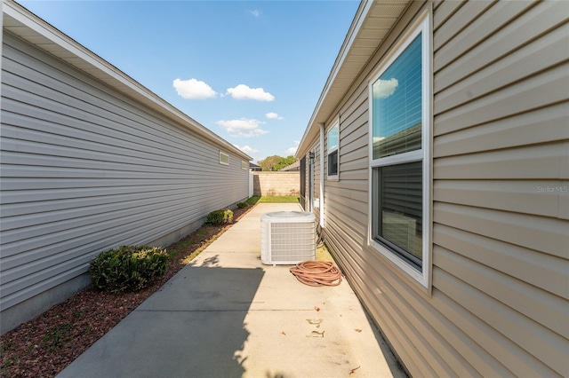 view of side of property featuring cooling unit, a patio, and fence