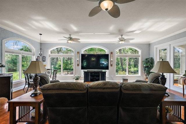 living area with wood finished floors, ornamental molding, and a ceiling fan