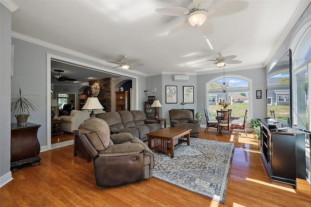 living room with wood finished floors, arched walkways, ceiling fan, and ornamental molding