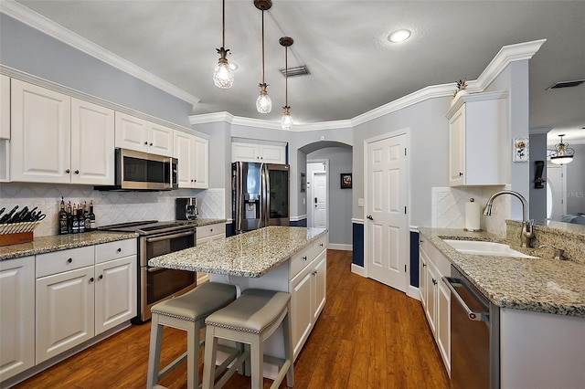 kitchen featuring visible vents, a center island, white cabinetry, arched walkways, and appliances with stainless steel finishes