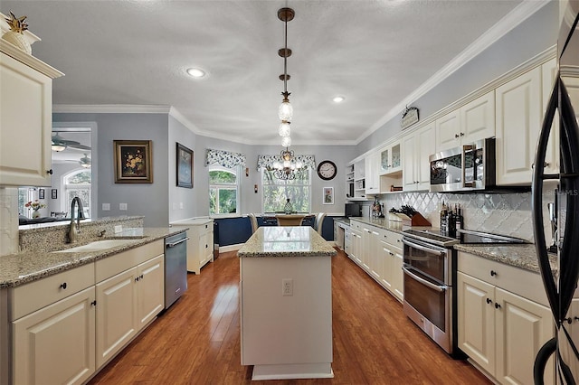 kitchen featuring a sink, tasteful backsplash, a kitchen island, wood finished floors, and stainless steel appliances