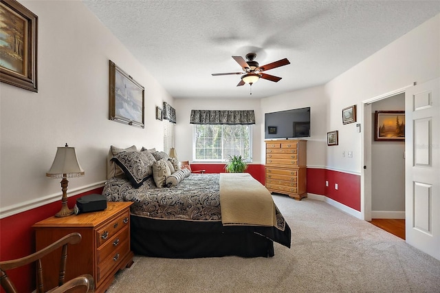 carpeted bedroom with a ceiling fan, baseboards, and a textured ceiling