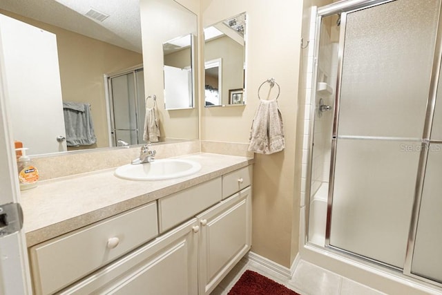 bathroom with vanity, a shower stall, visible vents, and a textured ceiling