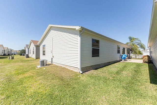 view of side of property with a yard, fence, and central AC