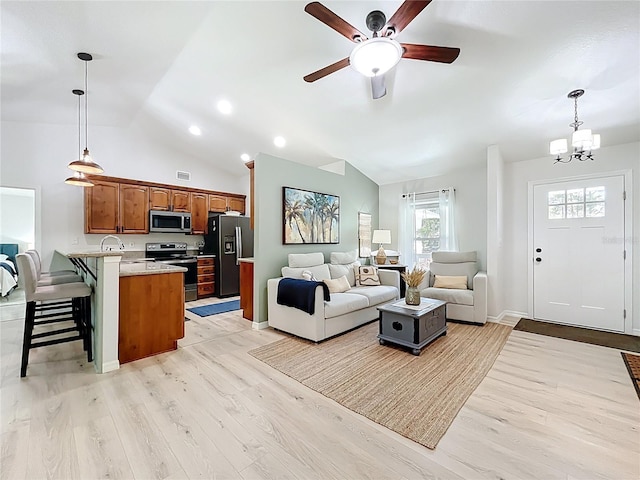 living room featuring lofted ceiling, light wood-style flooring, ceiling fan with notable chandelier, and baseboards