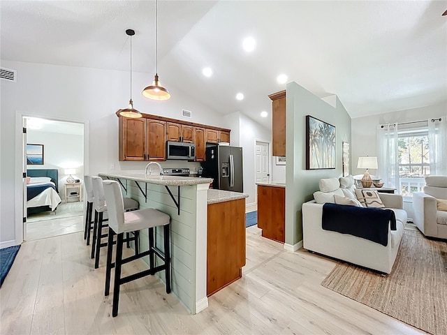 kitchen with a breakfast bar, a peninsula, stainless steel microwave, fridge with ice dispenser, and open floor plan