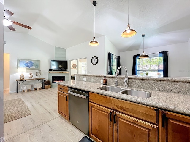 kitchen featuring brown cabinets, a sink, stainless steel dishwasher, lofted ceiling, and ceiling fan