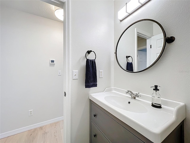 bathroom with vanity, wood finished floors, and baseboards