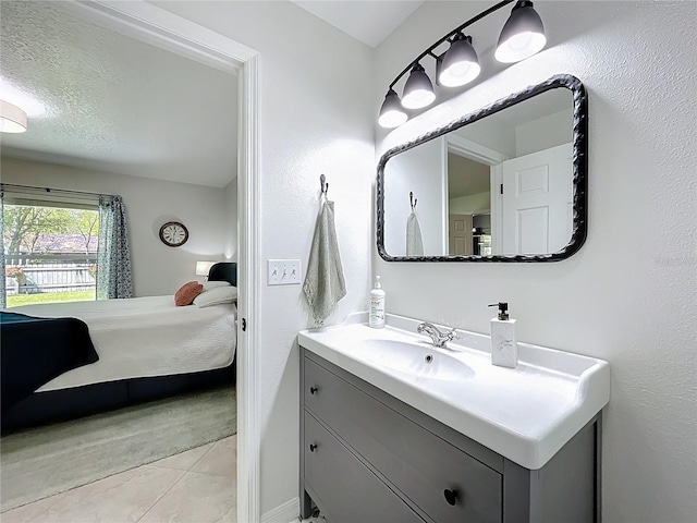 ensuite bathroom with connected bathroom, a textured ceiling, vanity, and tile patterned flooring