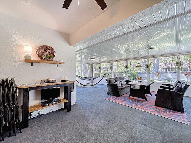 carpeted living area with a ceiling fan, a textured wall, and a healthy amount of sunlight