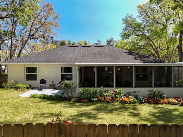 back of property featuring a patio area, a lawn, a sunroom, and a shingled roof