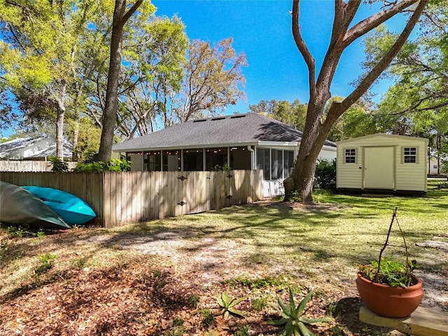 rear view of house with fence, a yard, a storage shed, an outdoor structure, and a sunroom