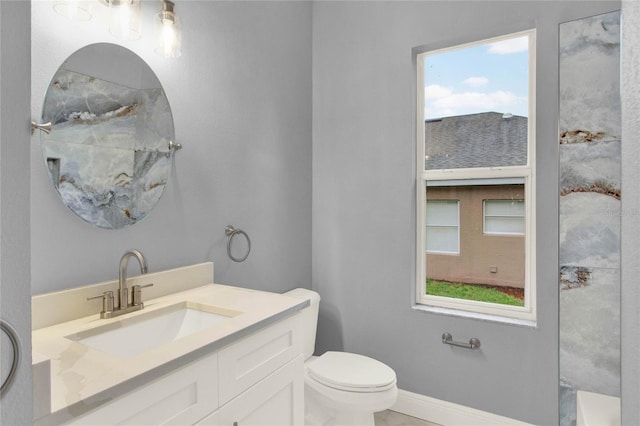 full bath featuring toilet, vanity, and baseboards