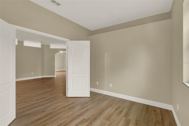 empty room with wood finished floors, visible vents, and baseboards