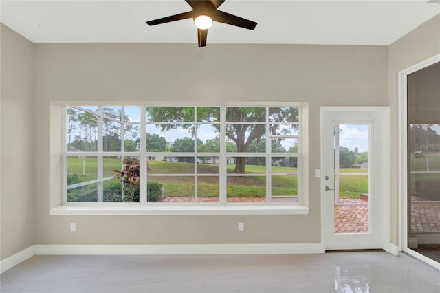 unfurnished sunroom featuring a wealth of natural light and a ceiling fan