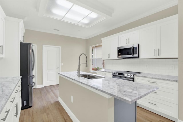 kitchen with a kitchen island with sink, a sink, tasteful backsplash, stainless steel appliances, and white cabinets