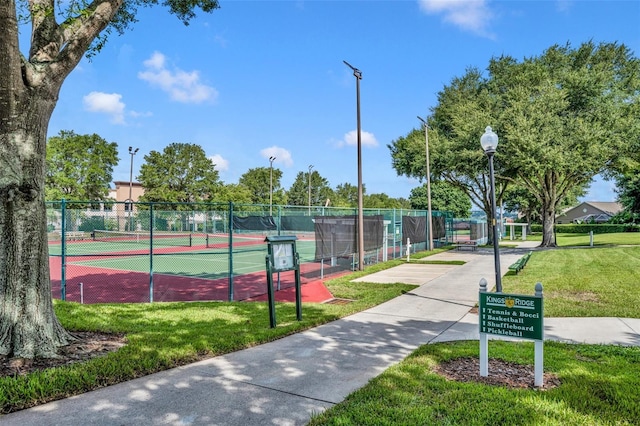 view of home's community featuring a tennis court, fence, and a lawn