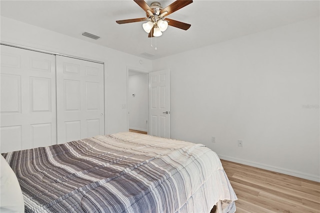 bedroom with visible vents, ceiling fan, baseboards, light wood-style floors, and a closet