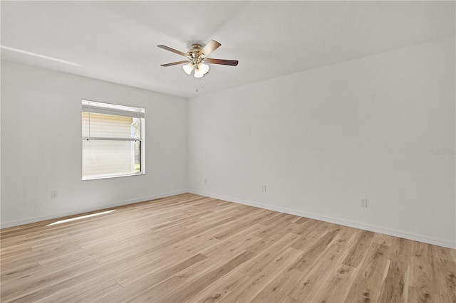 empty room with baseboards, a ceiling fan, and light wood-style floors