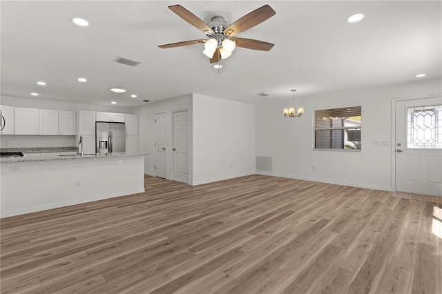 unfurnished living room featuring recessed lighting, visible vents, light wood-style flooring, and ceiling fan with notable chandelier