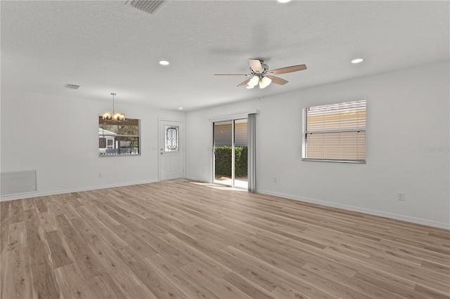 unfurnished living room with baseboards, ceiling fan with notable chandelier, visible vents, and light wood-type flooring