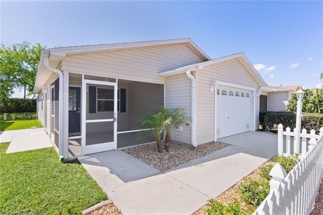 view of front facade with concrete driveway, fence, a garage, and a sunroom