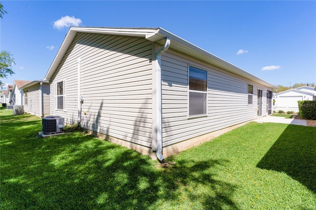 view of side of property with a yard and central AC