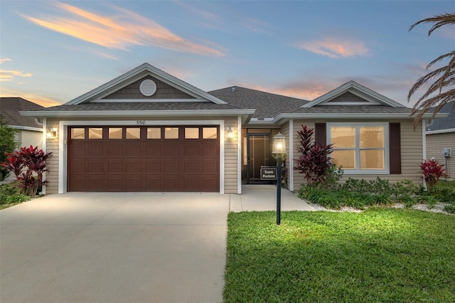 view of front of house with an attached garage, a lawn, and driveway