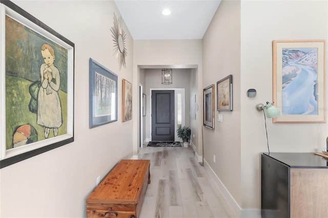 doorway featuring baseboards and light wood-style floors