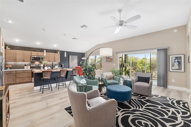 living area featuring visible vents, baseboards, lofted ceiling, light wood-style floors, and a ceiling fan