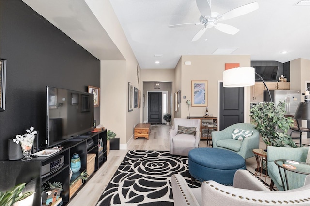 living area featuring ceiling fan, baseboards, and light wood-style flooring